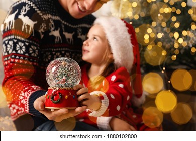 Father and daughter with snow globe near Christmas tree, focus on toy. Bokeh effect - Powered by Shutterstock