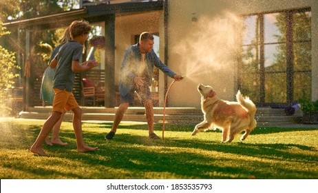 Father, Daughter, Son Play With Loyal Golden Retriever, Dog Tries to Catch Water from Garden Water Hose. Family Spending Fun Outdoors Time Together in Backyard. Golden Hour Sunset.
