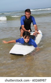 Father And Daughter Surfing In The Ocean