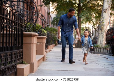 Father and daughter taking a walk down the street