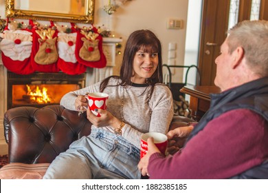 Father And Daughter Talk While Having A Hot Drink In Front Of The Fireplace