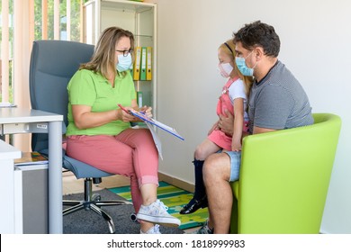 Father And Daughter At The Therapist Office In Assessment Meeting During Covid - 19 Pandemic Outbreak. Social Worker Talking To A Single Father During Interview.