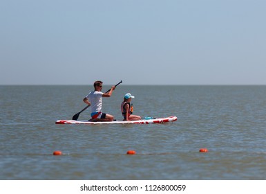 Father and daughter together paddling on a sup board