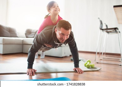 father and daughter are training at home. Workout in the apartment. Sports in home conditions. They make the doing plank. daughter climbed on dad. He is pushing up from the floor - Shutterstock ID 1741828838