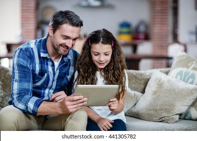 Father and daughter using digital tablet in living room at home - Powered by Shutterstock