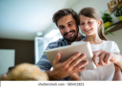 Father and daughter using digital tablet in the living room at home
