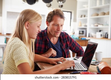Father and daughter using laptop computer at home