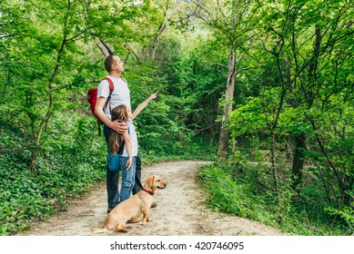 Father And Daughter Walking Through The Woods With Dog.