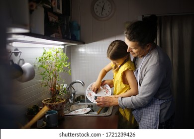 Father and daughter wash dishes in kitchen sink, Dad teaches kid wash dishes, helps child wash plate. life style in real interior in dark style, concept of fatherhood and man with household chores - Powered by Shutterstock