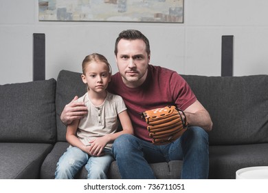 Father And Daughter Watching A Baseball Game Sitting On Sofa At Home