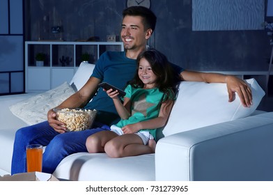 Father And Daughter Watching TV On Sofa At Night