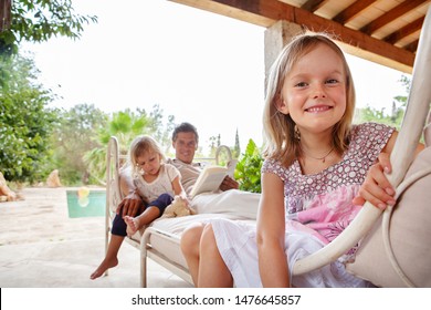 Father With Daughters In Home Swimming Pool Garden Relaxing Together, Smiling Outdoors. Beautiful Family Bonding Enjoying Holiday Villa, Summer Travel Abroad, Weekend Leisure Recreation Lifestyle.