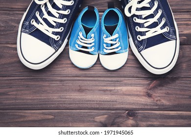 Father Day concept. Shoes of dad and son on brown wooden table