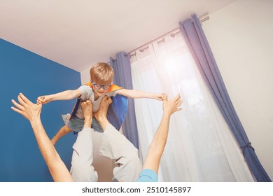 A father is enjoying playtime with his child imitate superhero flight by lifting her on a bed in a room filled natural light tones - Powered by Shutterstock