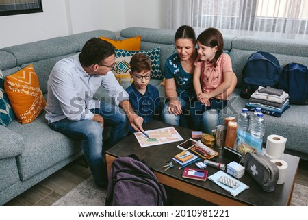 Father explaining to his family the assembly point map while preparing emergency backpacks