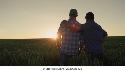 Father farmer hugging his adult son and watching the sunset over the field together. - Powered by Shutterstock