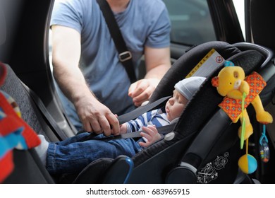 Father Fasten His Little Son In Car Seat