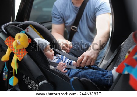Father fasten his little son in car seat Foto stock © 