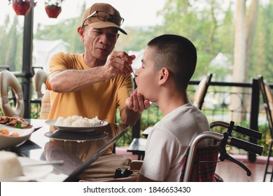 Father Feeding Food To Disabled Child On The Wheelchair In Home Or Restaurant,He Practiced Eating Food,Special Children's Lifestyle,Lifestyle In The Education Age Of Kids,Happy Disability Kid Concept.