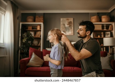 Father fixing his little girl's hair, preparing for a home workout - Powered by Shutterstock