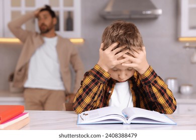 Father getting annoyed while son doing his homework in kitchen, selective focus. Dyslexia problem - Powered by Shutterstock