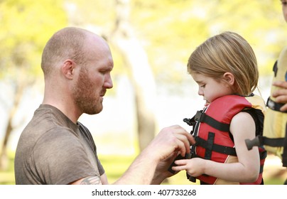 A Father Getting His Daughter Into A Life Jacket