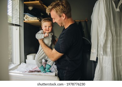 Father getting his son ready at home. Man at maternity leave taking care of his new born baby.
