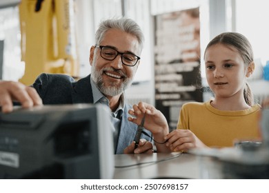 Father and girl during kid at work day, encouraging girl in career in robotics. Teacher showing young schoolgirl how to assemble small robot. - Powered by Shutterstock