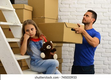 Father And Girl With Sad Or Bored Face. Moving In And Family Problem Concept. Dad And Daughter By Pile Of Cardboard Boxes And White Ladder. Man Holds Box And Kid Holds Bear On Light Room Background