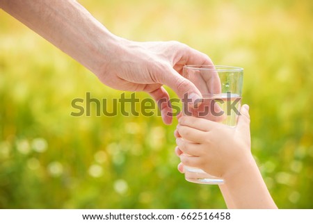 The father gives the child a glass of water. Selective focus.
