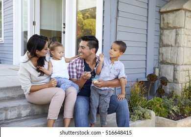 Father Giving Children Candy On Steps Outside Hose