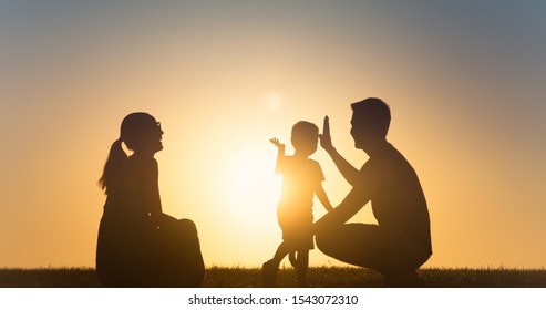 Father Giving High Five To His Son. Happy Family Silhouette, Having Fun Spending Time Together Outdoors At Sunset. 
