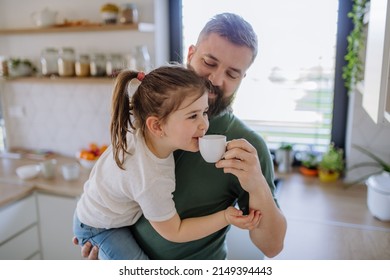 Father giving his little daughter cup with tea to drink at home. - Powered by Shutterstock