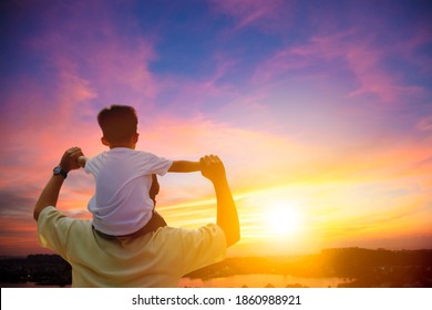 father giving son piggyback ride on his shoulders and looking the sunset - Powered by Shutterstock