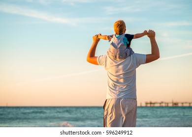 Father Giving Son Piggyback Ride On Beach