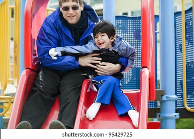 Father going down slide with disabled son who has cerebral palsy