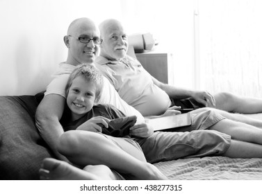 Father, Grandfather And Son Playing Games On Tablets And Reading Ebook