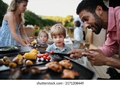 Father grilling meat and vegetable on grill during family summer garden party. - Powered by Shutterstock