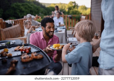 Father grilling meat and vegetable on grill during family summer garden party. - Powered by Shutterstock