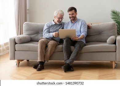 Father and grown up son sit on couch with laptop enjoy free time spending weekend in cozy living room at home, having fun chatting, younger generation teach older generation use of modern tech concept - Powered by Shutterstock