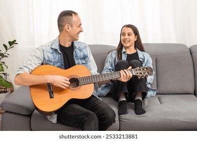 Father guy teaching girl teenager daughter guitar playing at home. Family musical lessons with strings instrument - Powered by Shutterstock