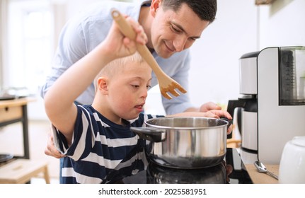 Father with happy down syndrome son indoors in kitchen, cooking. - Powered by Shutterstock