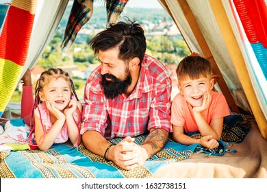 Father Have Fun With His Cute Daughter And Son. Happy Family Enjoy Being Together And Play. Young Hipster Bearded Dad Play With His Children At Colorful Playhouse At The Roof