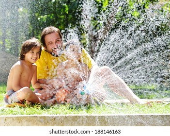 Father Having Fun With His Little Sons Holding Water Sprinkler