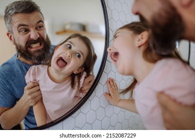 Father having fun with his little daughter, making grimaces in mirror in bathroom at home. - Powered by Shutterstock