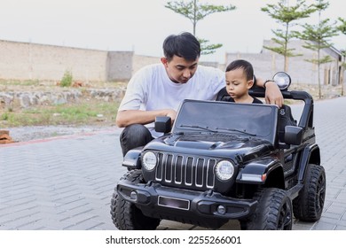 Father having fun with little son, ridingcar toy at the park.  - Shutterstock ID 2255266001