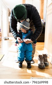 Father Helping Child, Putting On Winter Clothes For Snow Day