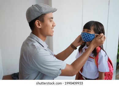 father helping her daughter to wear a mask before going to school in the morning to prevent from a covid 19 virus - Powered by Shutterstock