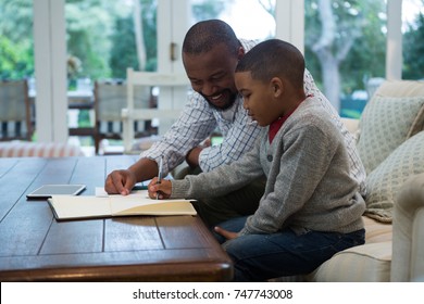 Father helping his son with homework in living room at home, Social distancing and self isolation in quarantine lockdown - Powered by Shutterstock