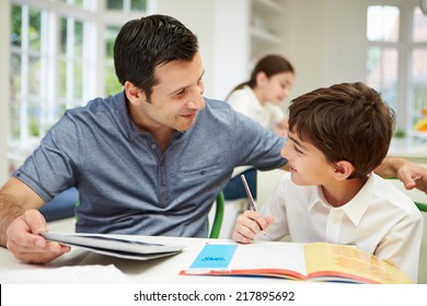 Father Helping Son With Homework Using Digital Tablet